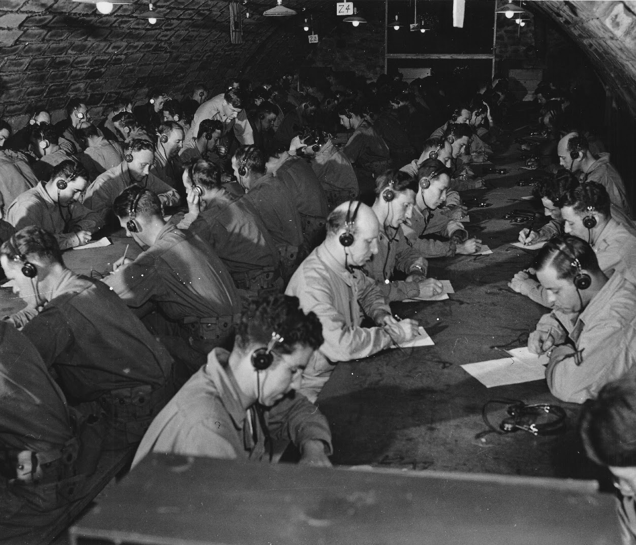 Soldiers at Camp Ritchie wearing headphones and writing at long tables